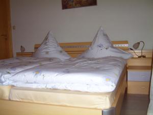 Una cama con sábanas blancas y almohadas. en Ferienwohnung Reisinger, en Arnbruck