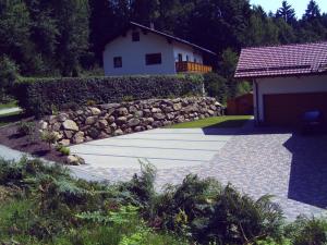 a garden with a stone wall and a house at Ferienwohnung Reisinger in Arnbruck +5 photos