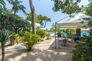 eine Terrasse mit einem Tisch, Stühlen und Bäumen in der Unterkunft Abamar Hotel in Santa Margherita di Pula