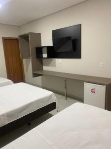 um quarto com 2 camas e uma televisão de ecrã plano em Hotel Colorado em Vilhena