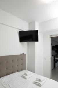 a bedroom with a bed with a television on the wall at Exclusive Ultracentral Apartments and Studios #Enescu#Universitatii#Suceava in Suceava