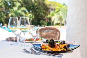 una mesa con un plato de comida y copas de vino en Abamar Hotel en Santa Margherita di Pula