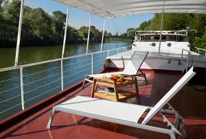 a boat with a table and a chair on the deck at Péniche Daphné's in Auvers-sur-Oise