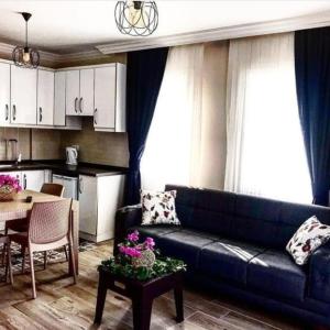 a living room with a blue couch and a kitchen at Apart TU Çeşme in Izmir