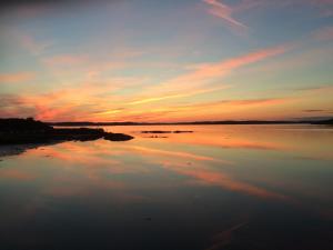 una puesta de sol sobre un gran cuerpo de agua en Kungälv-Kode Golf Club Bed & Breakfast, en Kode