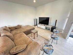 ein Wohnzimmer mit einem Sofa und einem Flachbild-TV in der Unterkunft Grand appartement proche de Délemont avec terrasse by Stay Swiss 