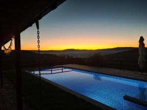 einen Pool mit Sonnenuntergang im Hintergrund in der Unterkunft A Casa da Japoneira CB in Rebordões