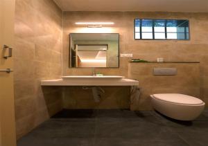 a bathroom with a sink and a toilet and a mirror at Avocado Cottages in Suntikoppa