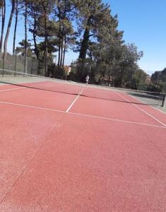 a person is playing tennis on a tennis court at Apartamento Esposende Quinta da Barca in Barca do Lago