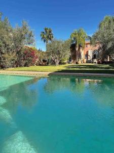une grande piscine d'eau en face d'une maison dans l'établissement Villa Nejma, à Marrakech