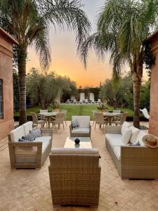 d'une terrasse avec des canapés, des tables et des palmiers. dans l'établissement Villa Nejma, à Marrakech