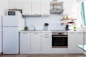 El Drago Apartment Fiber ,A/C,Near Ocean في طوستا ديل سيلونثيو: مطبخ ابيض مع دواليب بيضاء وثلاجة