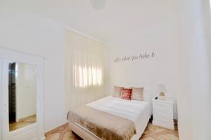 ein weißes Schlafzimmer mit einem Bett und einem Spiegel in der Unterkunft Stone's Throw - Front line apartment in Nazaré in Nazaré