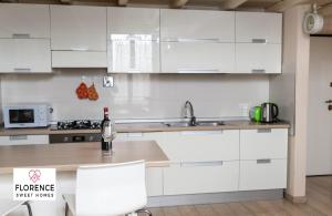 cocina con armarios blancos, fregadero y mesa en Matteotti Apartment en Scandicci