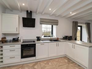 a kitchen with white cabinets and a sink at Rowan Barn in Hexham