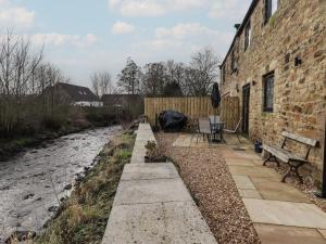 a brick building with a walkway next to a river at Rowan Barn in Hexham