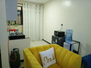a living room with a yellow couch and a kitchen at Mellow Homes 1 & 2 Bedrooms fully furnished Apartment in Kitengela 
