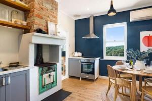 a kitchen and dining room with a table and a stove at Rossini's Cottage - Hills Escape in Mount Lofty