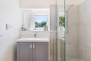 a bathroom with a sink and a glass shower at Rossini's Cottage - Hills Escape in Mount Lofty +17 photos