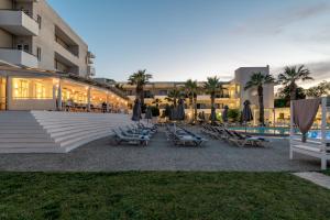 een groep stoelen en parasols naast een gebouw bij Gouves Bay by Omilos Hotels in Gouves