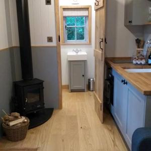 a kitchen with a woodburning stove in a tiny house at Finest Retreats - The Bakers Hut in Ashurst