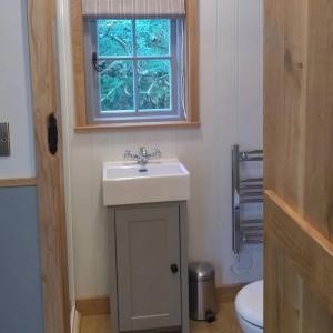 a bathroom with a sink and a window at Finest Retreats - The Bakers Hut in Ashurst