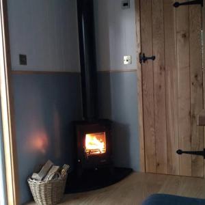 a fireplace in a living room with a fire in it at Finest Retreats - The Bakers Hut in Ashurst