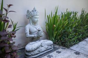 a statue in a garden with plants at Enigma Villa Canggu in Canggu