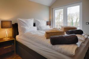 ein großes Bett mit weißen Kissen und einem Fenster in der Unterkunft Schloßappartements Heringsdorf in Heringsdorf