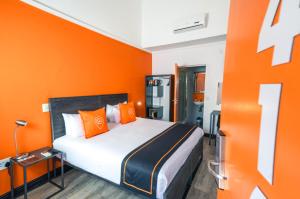 Cama en habitación con pared de color naranja en Never at Home Green Point en Ciudad del Cabo