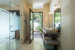 a bathroom with a sink and a glass door at Enigma Villa Canggu in Canggu