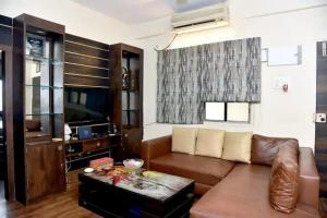 a living room with a brown couch and a tv at Orchid B&B in Kolkata