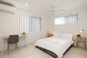 a white bedroom with a bed and a desk at Air Con! Laundry! Stylish! in Brisbane