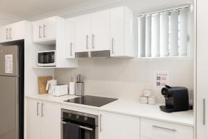 a white kitchen with white cabinets and a black appliance at Air Con! Laundry! Stylish! in Brisbane