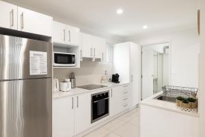 a kitchen with white cabinets and a stainless steel refrigerator at Air Con! Laundry! Stylish! in Brisbane