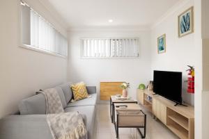 a living room with a couch and a tv at Aircon! Parking! Host with 100s of 5 star Reviews! in Brisbane