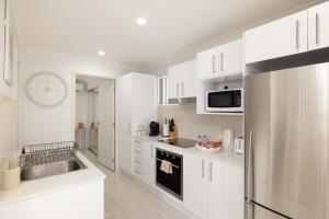 a kitchen with white cabinets and a stainless steel refrigerator at Aircon! Parking! Host with 100s of 5 star Reviews! in Brisbane