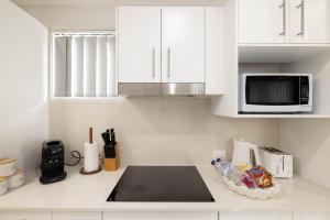 a white kitchen with a microwave and a counter top at Aircon! Parking! Host with 100s of 5 star Reviews! in Brisbane