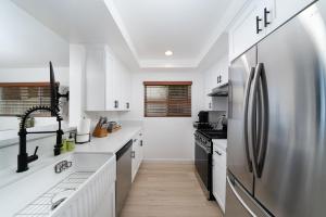 a kitchen with white counters and a stainless steel refrigerator at Downtown Beach Home, 5 min to Beach! Backyard, BBQ in Huntington Beach