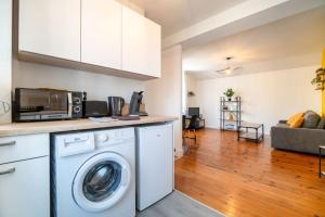 eine Küche mit einer Waschmaschine und ein Wohnzimmer in der Unterkunft L'industriel - Lourdes Centre in Lourdes