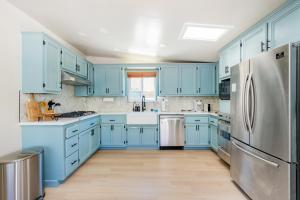 a kitchen with blue cabinets and a stainless steel refrigerator at Walk to Beach! Patio, Rooftop, Yard, BBQ! Downtown Huntington in Huntington Beach
