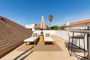 a patio with chairs and an umbrella on a roof at Walk to Beach! Patio, Rooftop, Yard, BBQ! Downtown Huntington in Huntington Beach