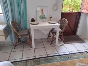 een witte tafel met twee stoelen en een tafel met borden erop bij Watercolour Cottage in Hermanus +11 foto's