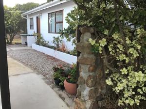 een stenen muur voor een huis met bloemen bij Watercolour Cottage in Hermanus
