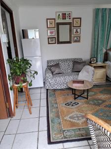 een woonkamer met een bank en een tafel bij Watercolour Cottage in Hermanus