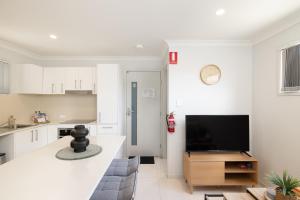 eine Küche und ein Wohnzimmer mit weißen Schränken und einem Flachbild-TV in der Unterkunft Aircon! Parking! Host with 100s of 5 star reviews! in Brisbane