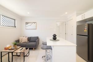 eine Küche und ein Wohnzimmer mit einem Sofa und einem Kühlschrank in der Unterkunft Aircon! Parking! Host with 100s of 5 star reviews! in Brisbane