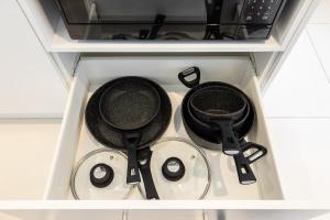 three pots and pans sitting on a stove in a drawer at Aircon! Parking! Host with 100s of 5 star reviews! in Brisbane