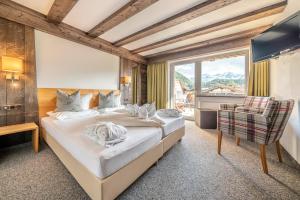 a bedroom with a bed and a chair and a window at Hotel Falknerhof in Niederthai