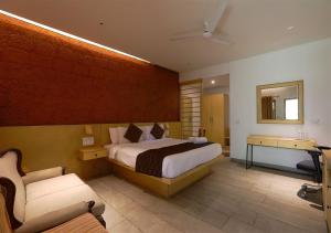 a bedroom with a bed and a couch and a television at Avocado Cottages in Suntikoppa